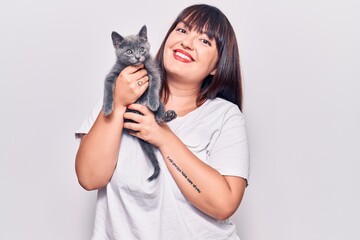 Young beautiful plus size woman smilling happy and confident. Standing with smile on face holding adorable cat over isolated white background