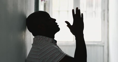 African man seeking God help and guidance, raising arms in air during desperate times