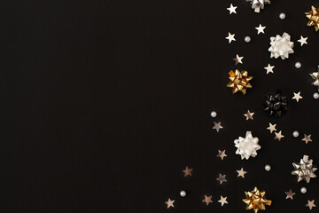 Christmas and winter compositions of festive bows, silver stars and pearls. Festive decor on a dark background. Top view, flat lay, copy space.
