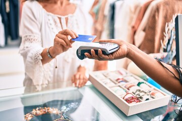 Woman paying purchase using credit card and dataphone at clothing store.