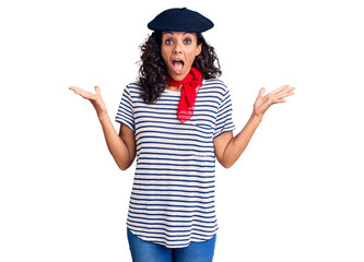 Middle age beautiful woman wearing french beret and scarf celebrating victory with happy smile and winner expression with raised hands