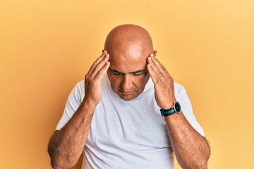 Obraz premium Mature middle east man wearing casual white tshirt with hand on head for pain in head because stress. suffering migraine.