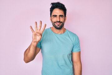 Fototapeta premium Handsome hispanic man with beard wearing casual clothes showing and pointing up with fingers number four while smiling confident and happy.