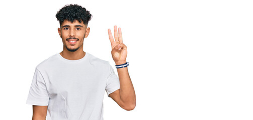 Young arab man wearing casual white t shirt showing and pointing up with fingers number three while smiling confident and happy.
