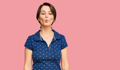 Young brunette woman with short hair wearing casual clothes making fish face with lips, crazy and...