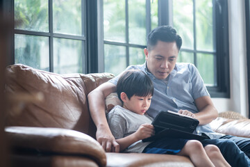 Asian young father teaching his son for lesson on E-learning classes.