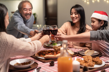 Asian big family clinking wine glasses and enjoying Christmas party.