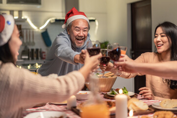 Asian big family clinking wine glasses and enjoying Christmas party.