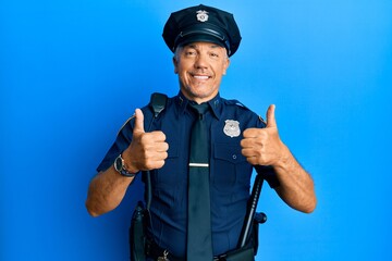 Handsome middle age mature man wearing police uniform success sign doing positive gesture with hand, thumbs up smiling and happy. cheerful expression and winner gesture.