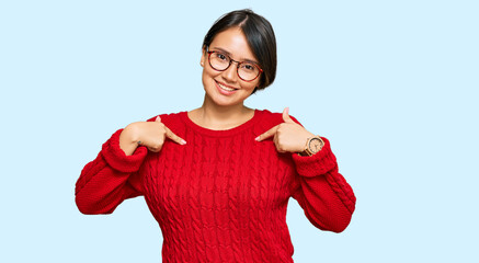 Young beautiful hispanic woman with short hair wearing casual sweater and glasses looking confident...
