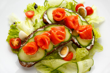 Norwegian Breakfast consisting of salmon and cucumber sandwiches, lettuce leaves and an egg