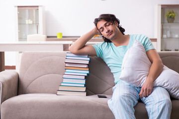Young male student being tired preparing for exams at home