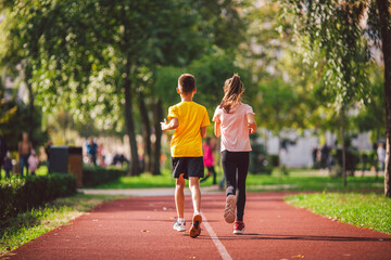 Child fitness, twins kids running on stadium track in city park , training and children sport...