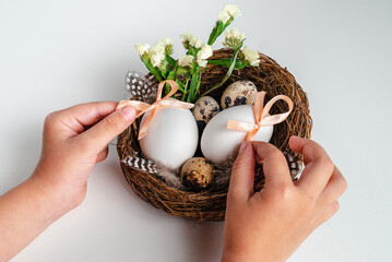 Child holding Easter eggs and flowers in  nest on white background. Greeting card