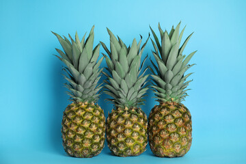 Ripe juicy pineapples on light blue background