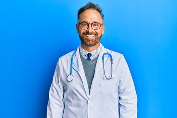 Handsome middle age man wearing doctor uniform and stethoscope with a happy and cool smile on face....