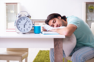 Young male student preparing for exams in time management concep