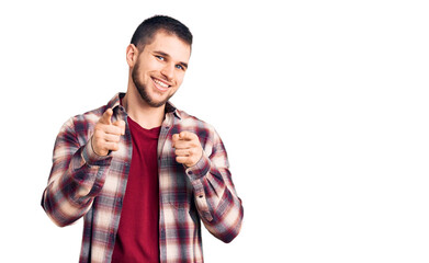 Naklejka premium Young handsome man wearing casual shirt pointing fingers to camera with happy and funny face. good energy and vibes.