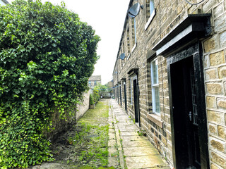 Fototapeta na wymiar Narrow back street, with trees, grass and Victorian stone cobbles, close to Victoria street in, Skipton, Yorkshire, UK