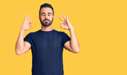Fototapeta premium Young hispanic man wearing casual clothes relax and smiling with eyes closed doing meditation gesture with fingers. yoga concept.