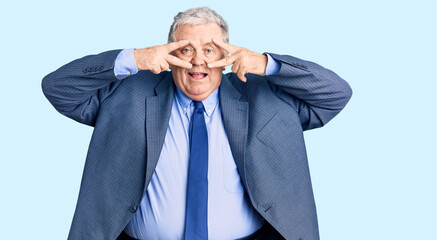 Senior grey-haired man wearing business jacket doing peace symbol with fingers over face, smiling cheerful showing victory