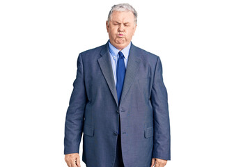 Senior grey-haired man wearing business jacket puffing cheeks with funny face. mouth inflated with air, crazy expression.