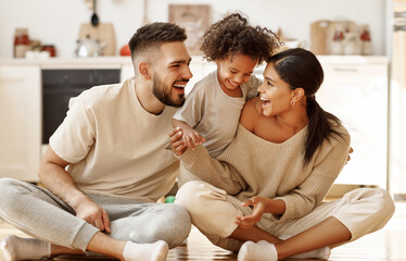 happy multiethnic family mom, dad and child  laughing, playing and tickles    on floor in cozy kitchen at home. - 387892167