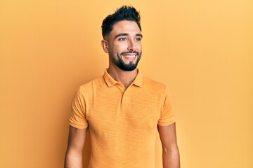 Young man with beard wearing casual clothes looking to side, relax profile pose with natural face and confident smile.