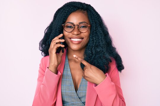 Beautiful african woman having conversation talking on the smartphone smiling happy pointing with hand and finger