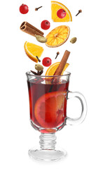 Cut orange, cranberries and different spices falling into glass cup of mulled wine on white background