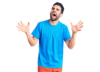 Naklejka premium Young handsome man with beard wearing casual t-shirt crazy and mad shouting and yelling with aggressive expression and arms raised. frustration concept.