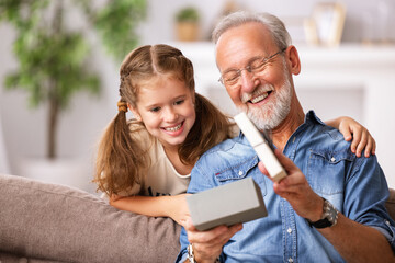 Grandfather and granddaughter opening present.
