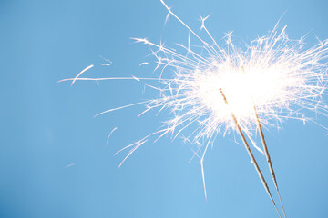 Bright burning sparklers on light blue background, closeup