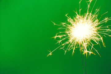 Bright burning sparklers on green background, closeup. Space for text