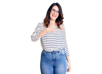 Beautiful young brunette woman wearing casual clothes and glasses doing happy thumbs up gesture with hand. approving expression looking at the camera showing success.