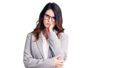 Beautiful young brunette woman wearing business clothes and glasses thinking looking tired and bored with depression problems with crossed arms.