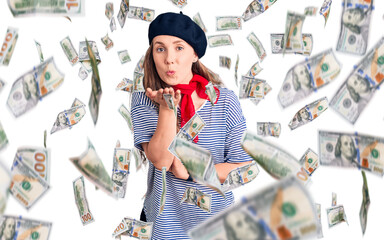 Young beautiful blonde woman wearing french beret and striped t-shirt looking at the camera blowing a kiss with hand on air being lovely and sexy. love expression.