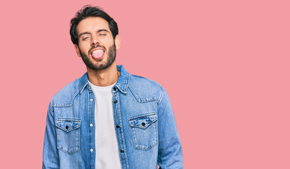 Young hispanic man wearing casual clothes sticking tongue out happy with funny expression. emotion concept.