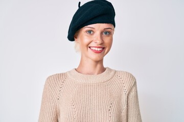 Young blonde woman wearing french look with beret looking positive and happy standing and smiling with a confident smile showing teeth