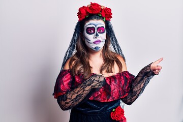 Young woman wearing day of the dead costume over white pointing aside worried and nervous with both hands, concerned and surprised expression