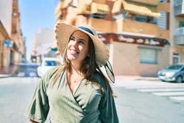 Young hispanic woman on vacation smiling happy walking at street of city