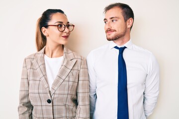 Beautiful couple wearing business clothes smiling looking to the side and staring away thinking.