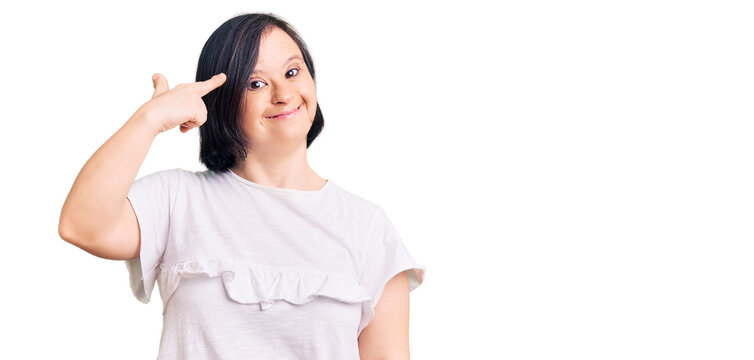 Brunette woman with down syndrome wearing casual white tshirt shooting and killing oneself pointing hand and fingers to head like gun, suicide gesture.