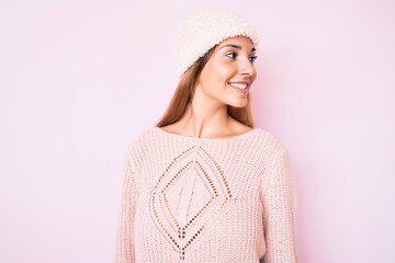 Young brunette woman wearing winter hat and sweater looking to side, relax profile pose with...