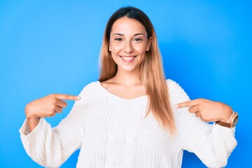 Young brunette woman wearing casual sweater looking confident with smile on face, pointing oneself...