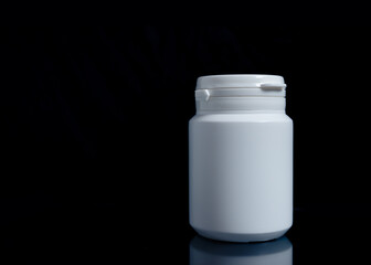 White medicine bottle on black background, medical concept.