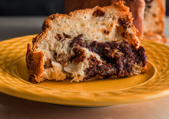 Traditional Christmas panettone (Chocottone) on yellow plate. Delicious panettone slice, traditional Italian dessert for Christmas. Close up
