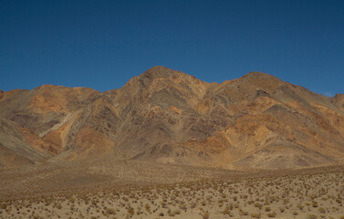 The Andes mountain range. View of  arid desert, sand, flora, rock and sandstone mountains under a blue sky.