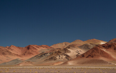 The Andes mountain range. Panorama view of the beautiful brown mountains high in the cordillera, under a deep blue sky. 