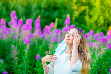 The girl took off her medical mask in the summer against the background of bright colors and happily closed her eyes. End of quarantine concept